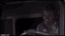 a man is laughing while driving a truck in a movie .