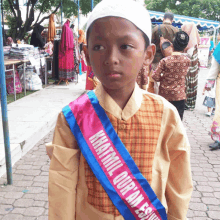 a boy wearing a sash that says khatmil quran