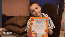 a young boy is holding up a certificate that says nessuni