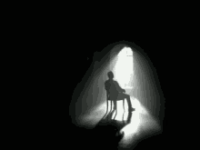 a silhouette of a man sitting in a chair in front of a window