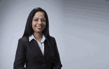 a woman in a black suit and white shirt is smiling .