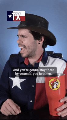 a man wearing a cowboy hat and a texas shirt is holding a cup