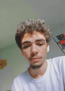 a young man with curly hair and a beard is wearing a white shirt