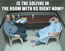 a man in a hospital gown sits in a chair talking to a police officer while another man sits at a table