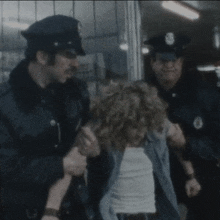 a group of police officers are holding a woman in their hands