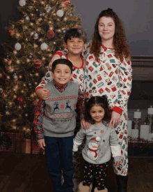 a family poses in front of a christmas tree and fireplace