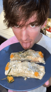 a young man licks a piece of fish on a blue plate