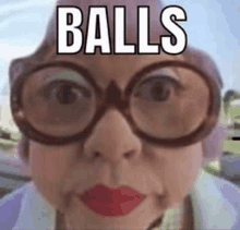 an elderly woman wearing glasses and a pink hat with the words `` balls '' written on it .