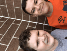 two boys are posing for a picture with one wearing an orange shirt that says umbro