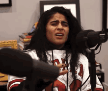 a woman is singing into a microphone while wearing a jersey that says chicago bulls .