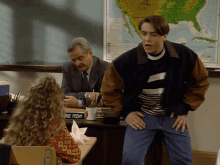 a man stands in front of a desk with a sign that says age feeny