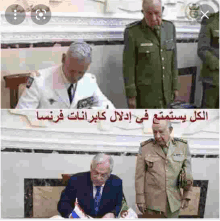 a group of men in military uniforms are signing a document in a room .