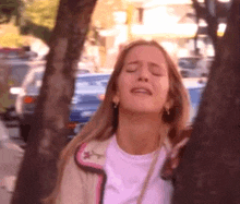 a woman with her eyes closed is standing under a tree