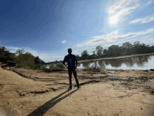 a person standing on a dirt road near a body of water