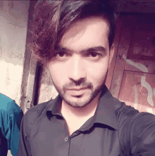 a man in a black shirt takes a selfie in front of a wooden door