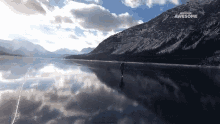 a man is walking on a frozen lake with mountains in the background and the words awesome on the bottom