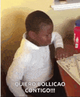 a young boy in a white shirt is sitting at a table with his eyes closed and a plate on it .