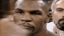 a close up of a boxer 's face in a boxing ring with a group of men behind him .