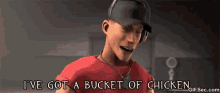 a man in a baseball cap is holding a bucket of chicken in front of his face .