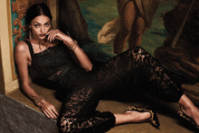 a woman in a black lace outfit is laying on the floor