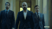 three men in suits and ties are walking down a hallway with a netflix logo behind them