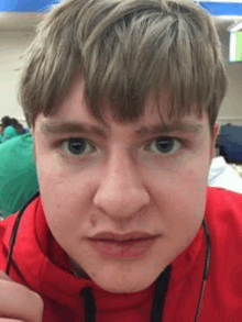 a close up of a young man 's face wearing a red hoodie .