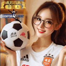 a woman wearing glasses holds a soccer ball in front of a museum bola ad