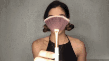 a woman is holding a brush in front of her face