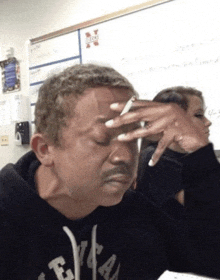 a man smoking a cigarette in front of a white board that has the letter n on it