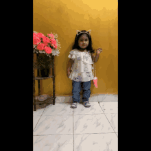 a little girl wearing a cat ear headband is standing in front of a yellow wall