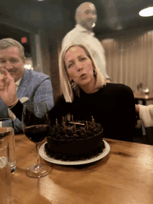 a woman blows out the candles on a chocolate cake