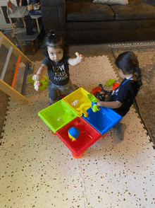 a little girl wearing a shirt that says " love your mother " is playing with toys