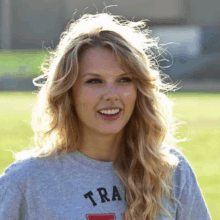 taylor swift is wearing a gray t-shirt that says tra on it .