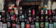 a row of bottles of beer are lined up in a row in front of a window .