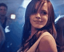 a woman is standing in a crowd of people in a club and smiling .