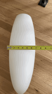 a yellow tape measure is measuring a white object