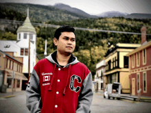 a man wearing a red and grey varsity jacket that says canada on it