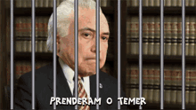 a man in a suit and tie is behind bars with the words " prenderam o temer " written below him