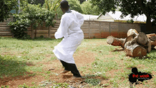 a man in a white robe is dancing in a yard with a sign that says the week on it