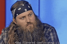 a man with a beard wearing a bandana and a plaid shirt says bbq flavored confusion .