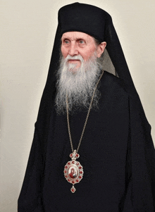 a man with a beard wearing a black robe and a necklace with a picture of jesus on it