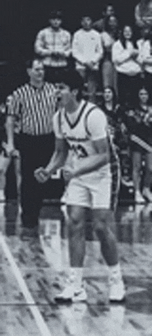 a black and white photo of a basketball player standing on a court .