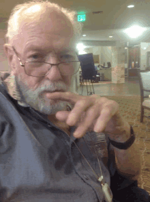 a man with glasses and a beard looks at the camera with an exit sign in the background