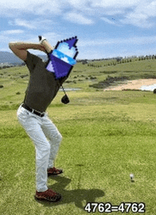 a man is swinging a golf club on a golf course while holding a bucket in front of his face .