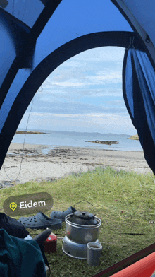 a picture of a beach from inside a tent with eidem written on the bottom right