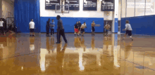 a group of men are playing basketball in a gym with a sign that says ' best basketball champions ' on it