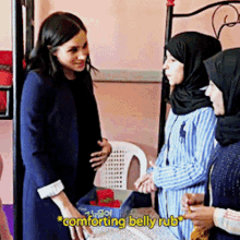 a woman in a blue jacket is talking to two other women and the words comforting belly rub are visible