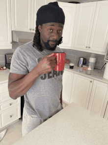 a man in a jean shirt is drinking from a red cup