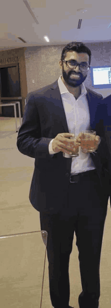 a man in a suit and glasses holds a glass in his hand