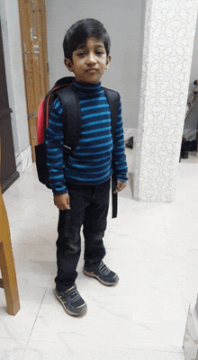 a young boy wearing a blue striped shirt and a black backpack